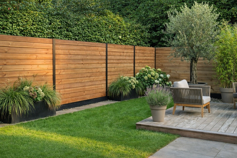 Horizontaal tuinscherm gemaakt met blokhutprofielen in thermowood naaldhout, geplaatst tussen zwarte metalen palen voor een moderne houten tuinafsluiting