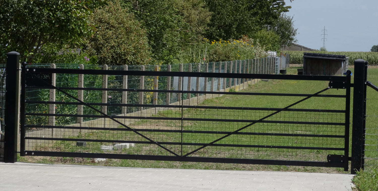 Landelijke weidepoort Meuhh van Kopal in zwart aluminium, prachtig geïntegreerd in een groene tuin met houten omheining.