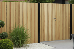 Modern scherm met verticale beplanking in iroko in combinatie met zwarte palen. 