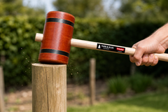 Houten houten hamer (moker) van Prindal die een houten paal in de grond slaat in een tuinomgeving