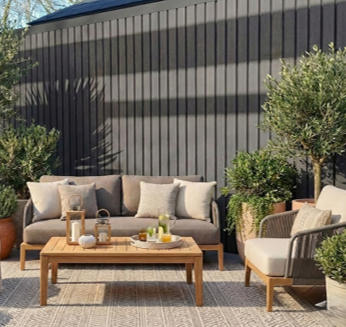 Moderne tuinwand bekleed met Fiberdeck WEO 60 composiet in Dark Grey, met een strakke verticale lijnstructuur en houten uitstraling in een tuinsetting.